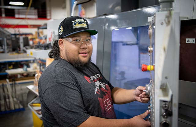 An AJAC apprentice uses a HAAS CNC machine to make a part at his company during his apprenticeship.