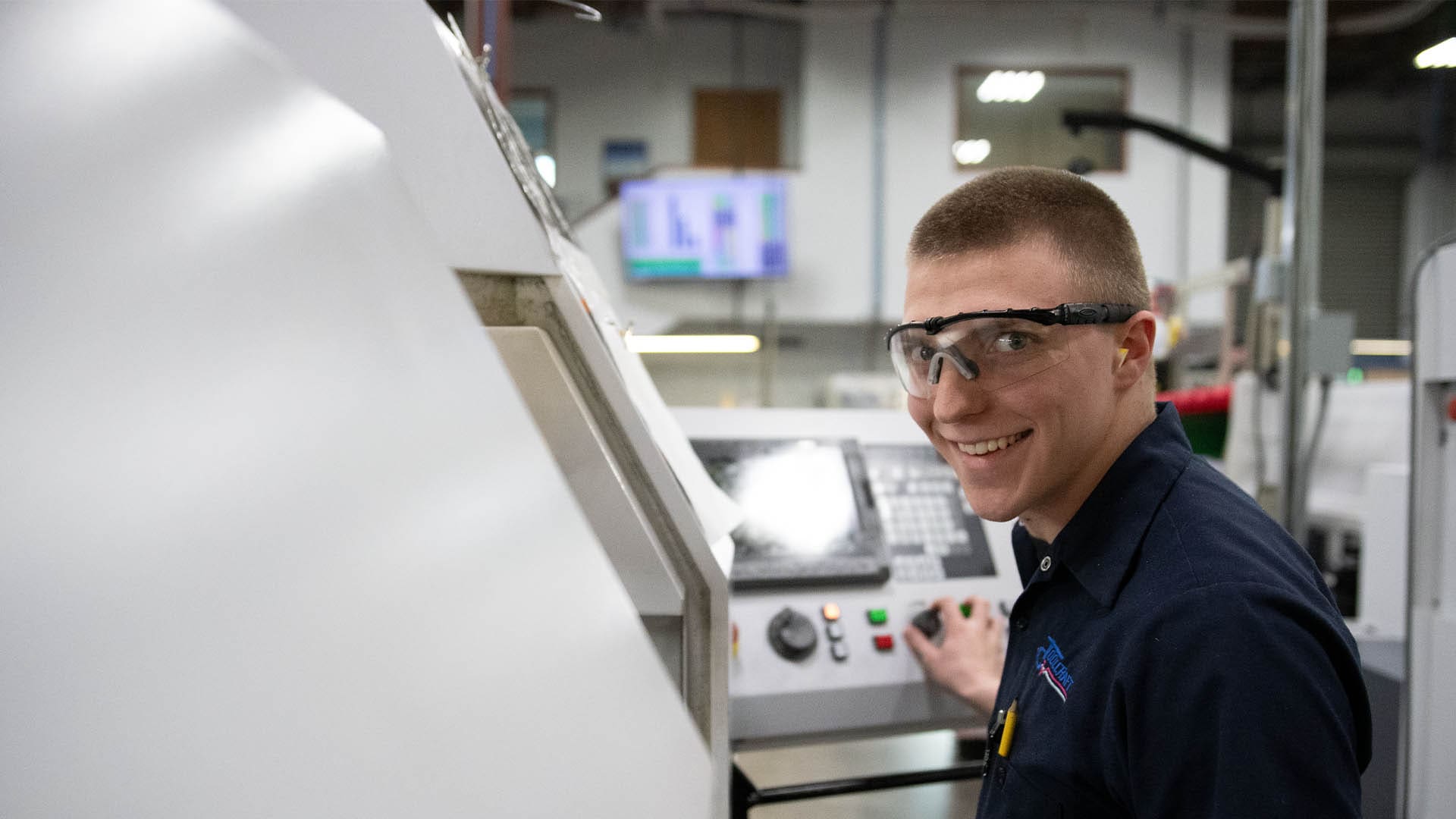 A production machine operator uses a CNC machine during his AJAC apprenticeship.